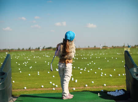 Little girl swinging golf club, rear viewの写真素材
