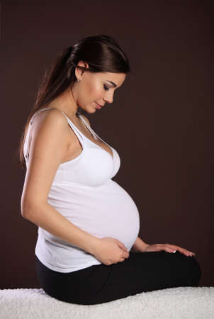 
Happy pregnant woman touching her belly near the brown wallの写真素材