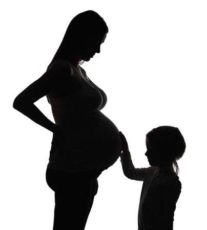 Silhouette of the pregnant woman with daughter isolated on whiteの写真素材