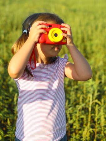 Portrait of the little girl with toy camera in summer fieldの写真素材