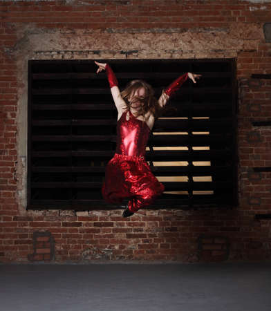 Young smiling blonde girl dancing over brick wall