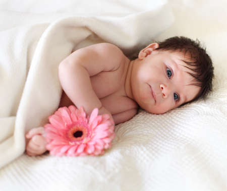 Portrait of a baby with flower lying on the bed. One month oldの写真素材