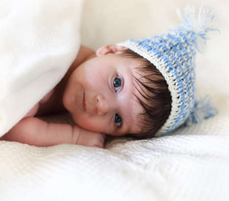 Portrait of a baby in knitting hat lying on the bed. One month oldの写真素材