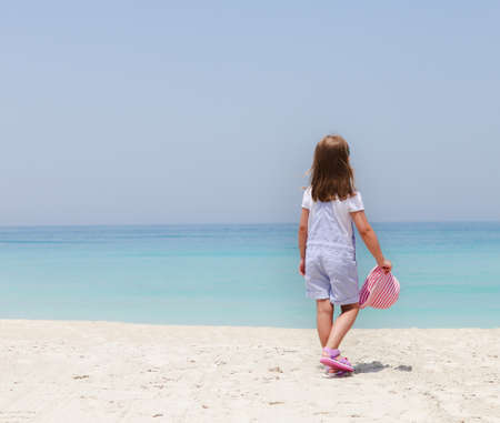 Little girl with hat on the beachの写真素材