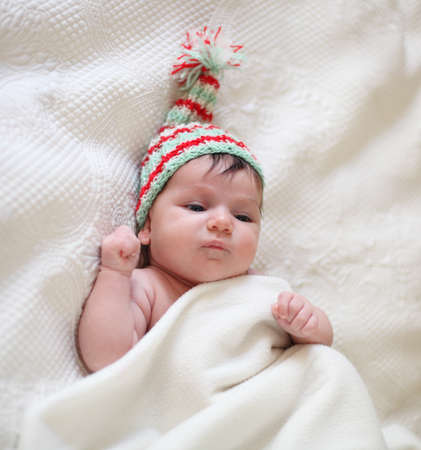 Portrait of a baby in knitting hat lying on the bed. One month old