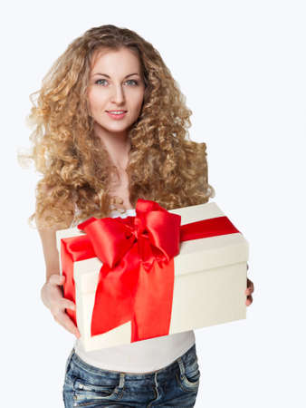Beautiful young blond girl holding present decorated with red ribbonの写真素材