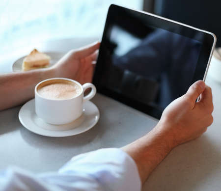 Man holding tablet computer in cafe. Close up