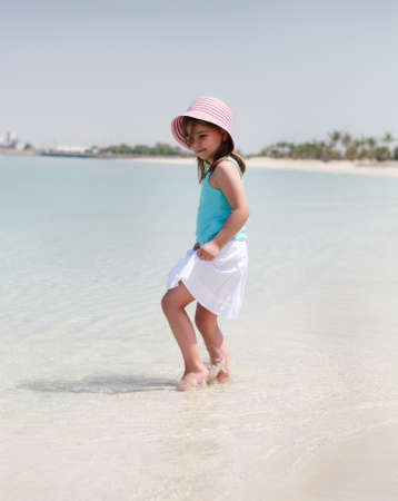Little happy girl in hat on the beachの写真素材