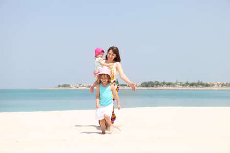Mother and her two little daughters having fun on the beachの写真素材