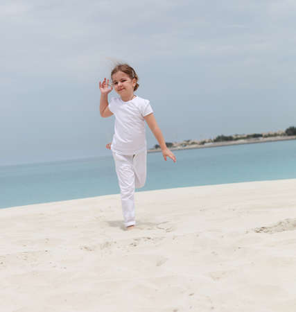 Little happy girl in white running on the beachの写真素材