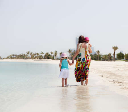 Mother and her two little daughters walking on the beachの写真素材
