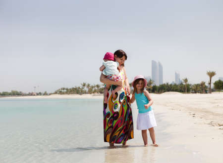 Mother and her two little daughters on the beachの写真素材