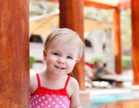 Little cute baby girl having fun in swimming poolの写真素材