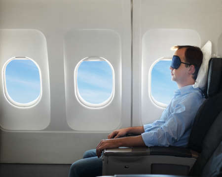 Portrait of man relaxing in sleaping mask in the airplaneの写真素材