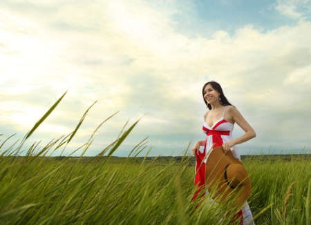 Brunette young woman with hat in summer day. Outdoors portraitの写真素材