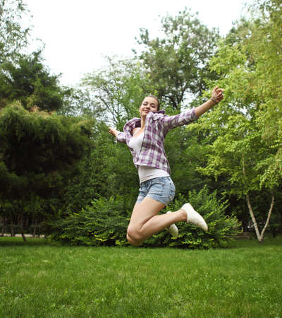 Brunette girl jumping in summer park. Outdoors potraitの写真素材