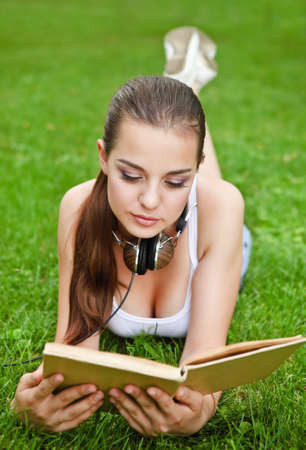 Beautiful young girl with book lying on the grass in summer park
の写真素材