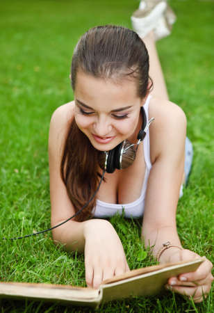 Beautiful young girl with book lying on the grass in summer park
の写真素材