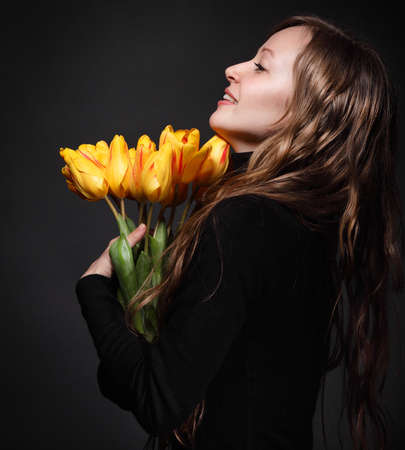 Happy blond  woman with bouquet of orange tulipsの写真素材