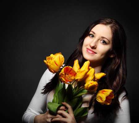 Happy brunette  woman with bouquet of orange tulipsの写真素材