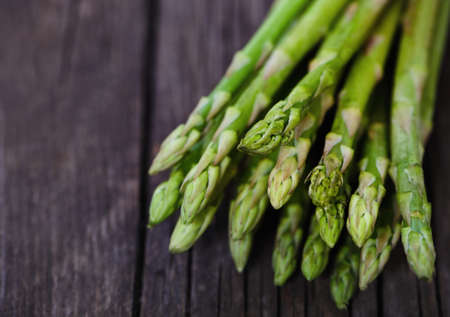 Bunch of fresh green asparagus spears on a rustic wooden table の写真素材
