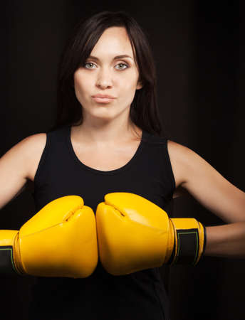 Portrait of a girl in yellow boxing gloves over dark backgroundの写真素材
