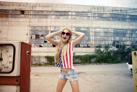 Blond girl holds hands on her head standing on damaged gas stationの写真素材