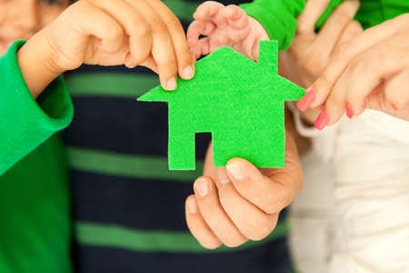 Family of four holding green house in hands. Conceptの写真素材
