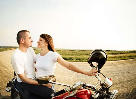 Young biker couple on the country road against the skyの写真素材