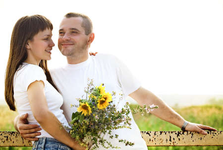 Happy young smiling couple with flowers outdoorsの写真素材