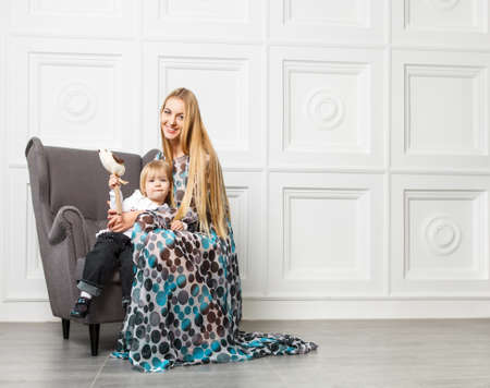 Portrait of the beautiful blond mother with little daughter in armchairの写真素材