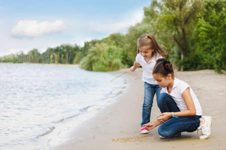 Happy children playing on the river coast in the summer dayの写真素材