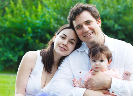 Happy young family with baby girl outdoors