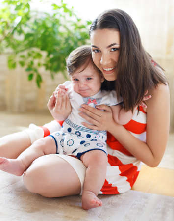 Happy smiling mother with eight month old baby girl indoor 