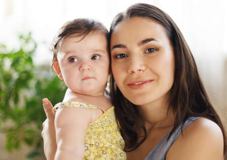 Happy smiling mother with eight month old baby girl indoor
