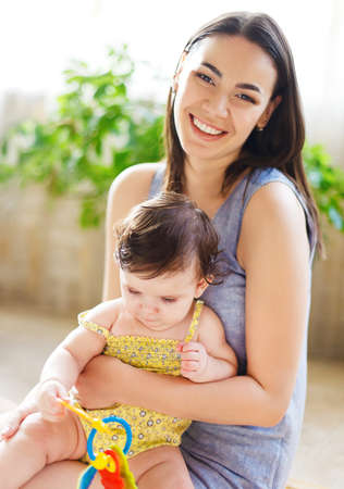 Happy smiling mother with eight month old baby girl indoorの写真素材