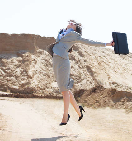 Happy businesswoman jumping in the air in a desertの写真素材