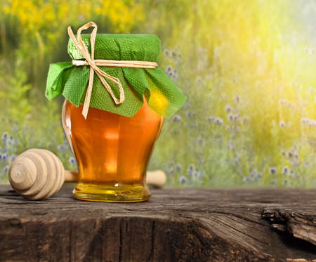 Honey jar on the wooden table against nature backgroundの写真素材