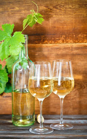 Still life with glasses of white wine, bottle and leavesの写真素材