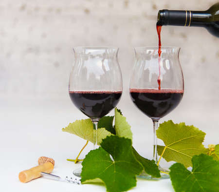 Still life with glasses of red wine, bottle and leaves of grape