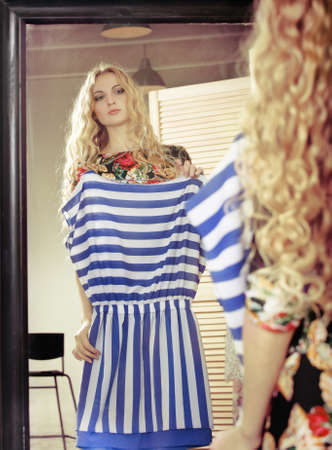 Woman shopping dresses looking in mirror in clothing store