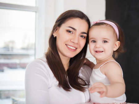 Happy smiling mother with one year baby girl indoorの写真素材