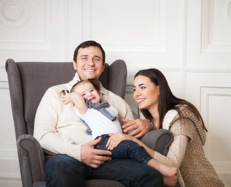 Happy smiling family with one year old baby girl indoorの写真素材
