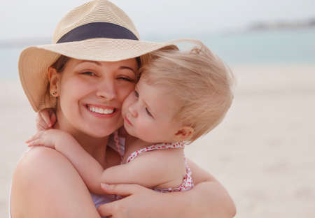 Portrait of mother holding her bay girl at beach in summerの写真素材