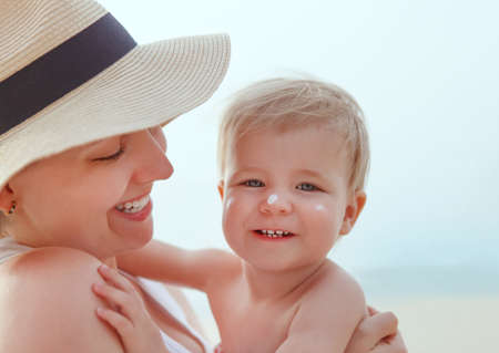 Portrait of mother holding her bay girl at beach in summerの写真素材