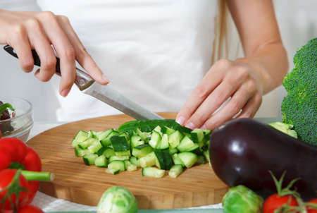 Hands of a woman cutting vegetables at the kitchenの写真素材