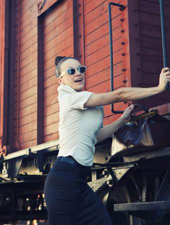 Woman with a suitcase standing on the platform near the retro trainの写真素材