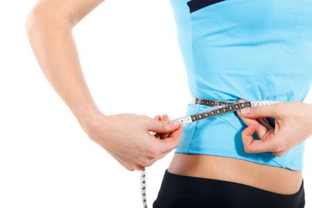 Young slim woman measuring her stomach with measuring tape