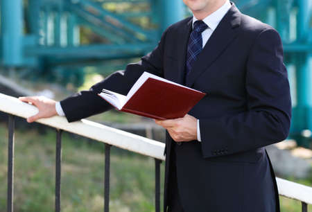 Close up of the hands of the businessman with a note book. Outdoors