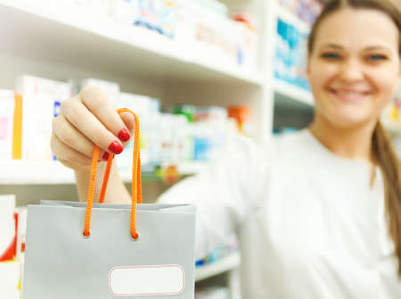 Female pharmacist holding packet in her hand at drugstore. Close upの写真素材